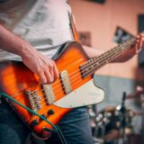 man in white t shirt playing brown electric guitar