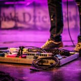 faceless musician with pedalboard in club